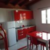 Cucina rossa con tavolo abbinato, letti a castello e finestra aperta.