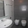 Un bagno moderno con lavabo, bidet e WC, piastrelle grigie e bianche.