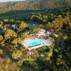 Vista aerea di un complesso con piscina circondato da alberi su una collina.