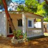 Bungalow bianco in mezzo agli alberi con sdraio blu.