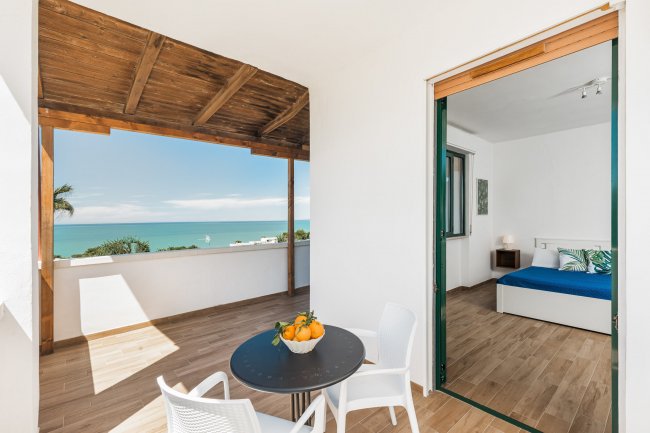 Vista sul mare con tavolo e sedie su un balcone.