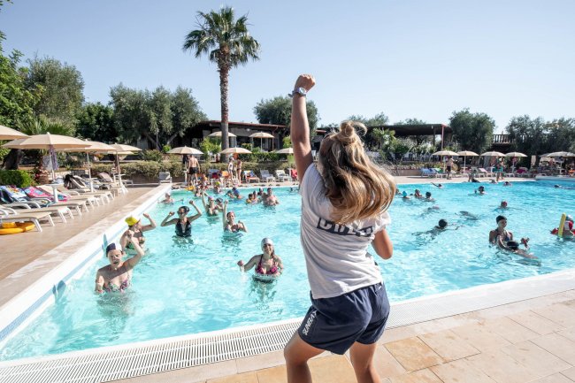 Animatrice conduce un'attività in piscina affollata.